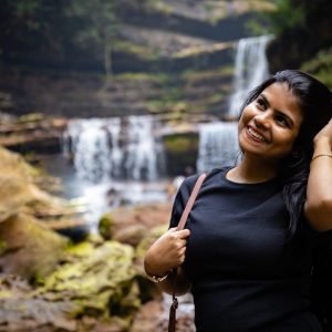 An Indian beautiful female in black dress smiling and enjoying the view in front of wei sawdong waterfall, Meghalaya, India