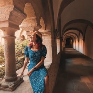 A girl traveler and tourist sits in the arch of an ancient monastery or the courtyard of the cathedral